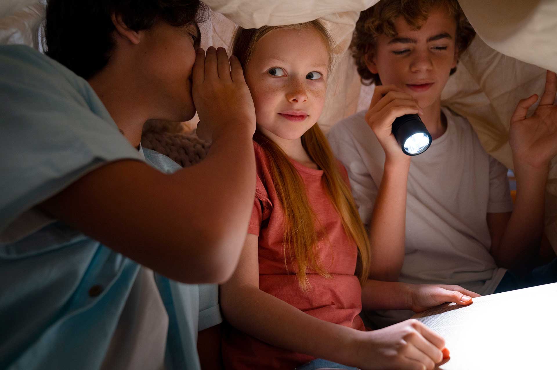 Kids sitting under a blanket in the museum at night